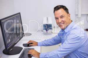 Portrait of happy dentist examining x-ray report on computer