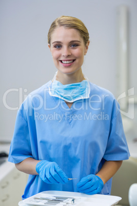 Portrait of happy female nurse holding dental tool