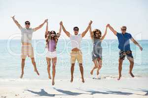 Friends jumping with arms raised at beach