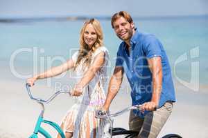 Smiling couple riding bicycles at beach