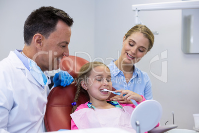 Dentist assisting young patient while brushing teeth