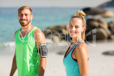 Happy couple in sports clothing standing at beach