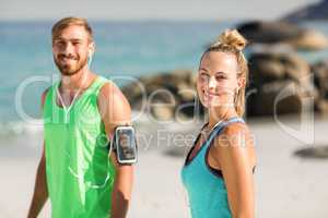 Happy couple in sports clothing standing at beach