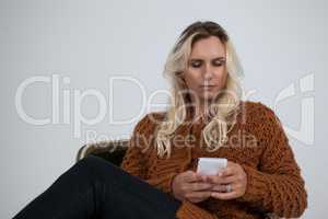 Transgender using mobile phone while sitting on chair