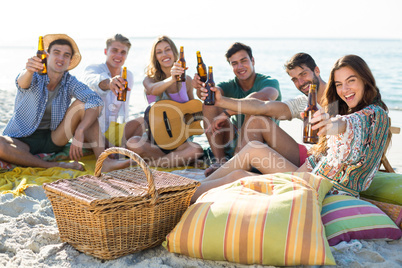 Friends having drinks while sitting at beach