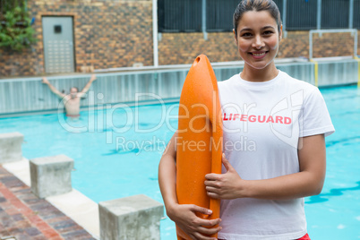 Lifeguard standing with rescue buoy at poolside