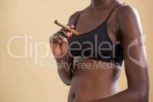 Androgynous person holding cigar against beige background