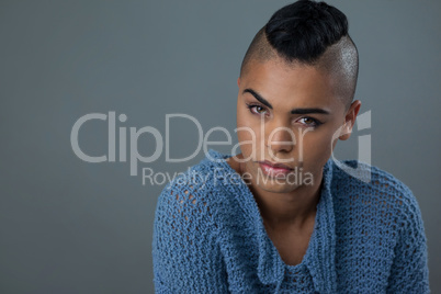 Transgender woman wearing blue sweater over gray background