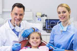 Portrait of dentist and nurse examining a young patient with tools