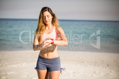Woman looking in wristwatch while standing at beach