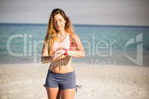 Woman looking in wristwatch while standing at beach