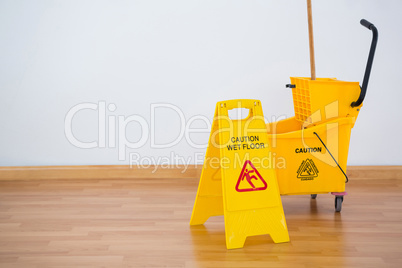 Yellow sigh boad with mop bucket on floor against wall