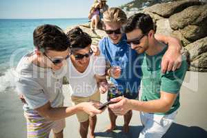 Cheerful male friends looking in smartphone