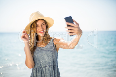 Woman smiling while taking selfie against sea