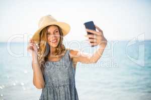Woman smiling while taking selfie against sea