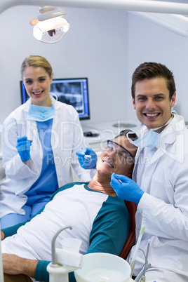 Portrait of dentists examining a male patient with tools