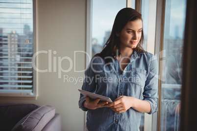 Woman holding digital tablet while looking through window