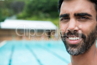 Smiling lifeguard standing near poolside