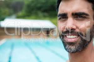 Smiling lifeguard standing near poolside