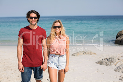 Couple wearing sunglasses while standing at beach