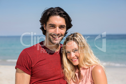 Young couple smiling while standing at beach