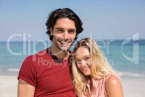 Young couple smiling while standing at beach