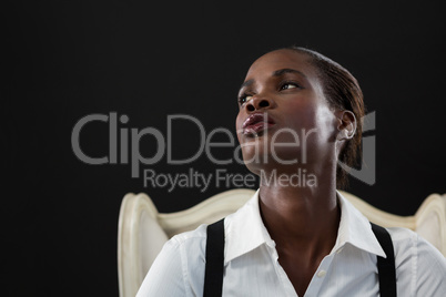 Androgynous man posing while sitting on a chair