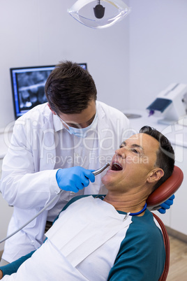 Dentist examining a male patient with tools