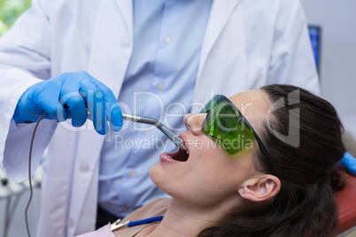 Dentist examining a female patient with dental equipment