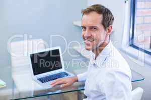 Portrait of smiling dentist working on laptop