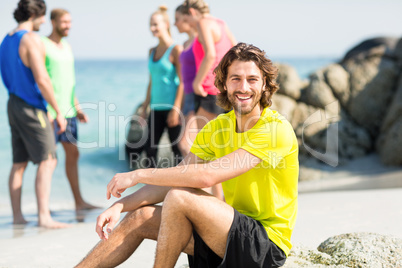Man sitting against friends at beach