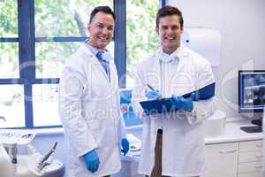 Portrait of happy dentists standing with file