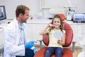 Smiling young patient brushing her teeth in dental clinic
