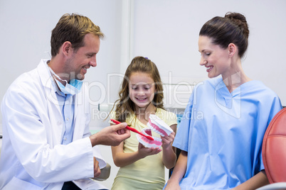 Dentists showing young patient how to brush teeth
