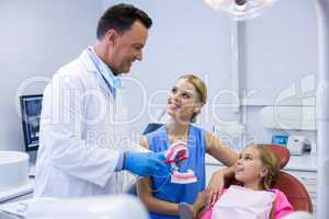 Dentist showing young patient how to brush teeth