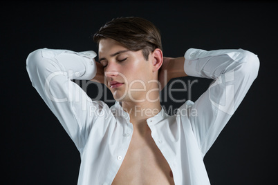 Androgynous man posing in open buttondown shirt with eyes closed