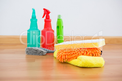 Cleaning sponge and chemical bottles on hardwoodfloor