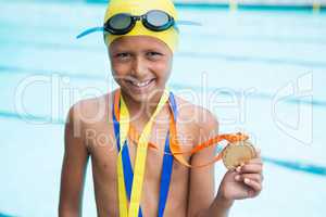 Boy with gold medals around his neck standing near poolside