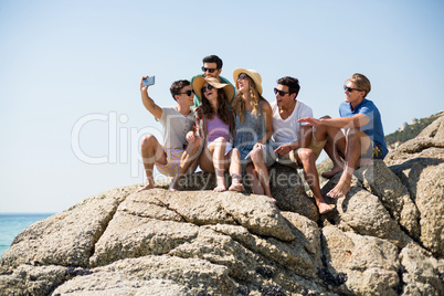 Friends taking selfie while sitting on rock formations