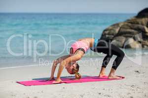 Side view of young woman exercising on exercise mat at beach