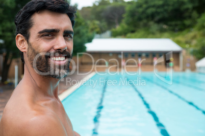 Smiling lifeguard standing near poolside