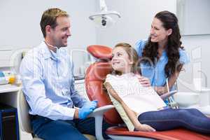 Dentist interacting with mother and daughter while dental examination