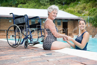 Female coach and senior woman smiling at poolside