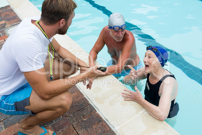 Swim coach interacting with senior couple