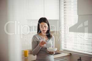 Woman using smart phone while holding bowl