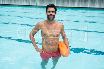 Man standing in swimming pool with rescue buoy