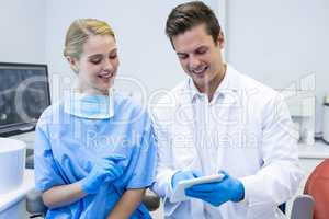Happy dentist and nurse using digital tablet