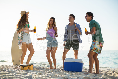 Friends having drink while dancing on shore at beach