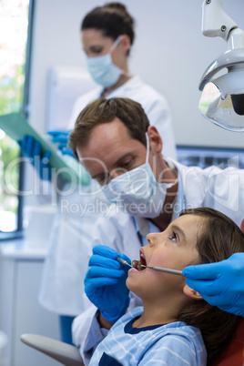 Dentist examining a young patient with tools