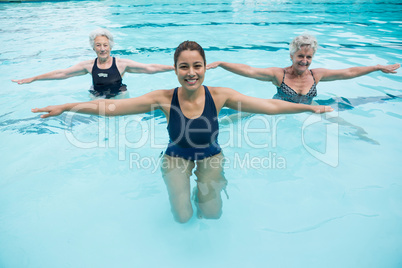 Female trainer with senior women exercising in swimming pool